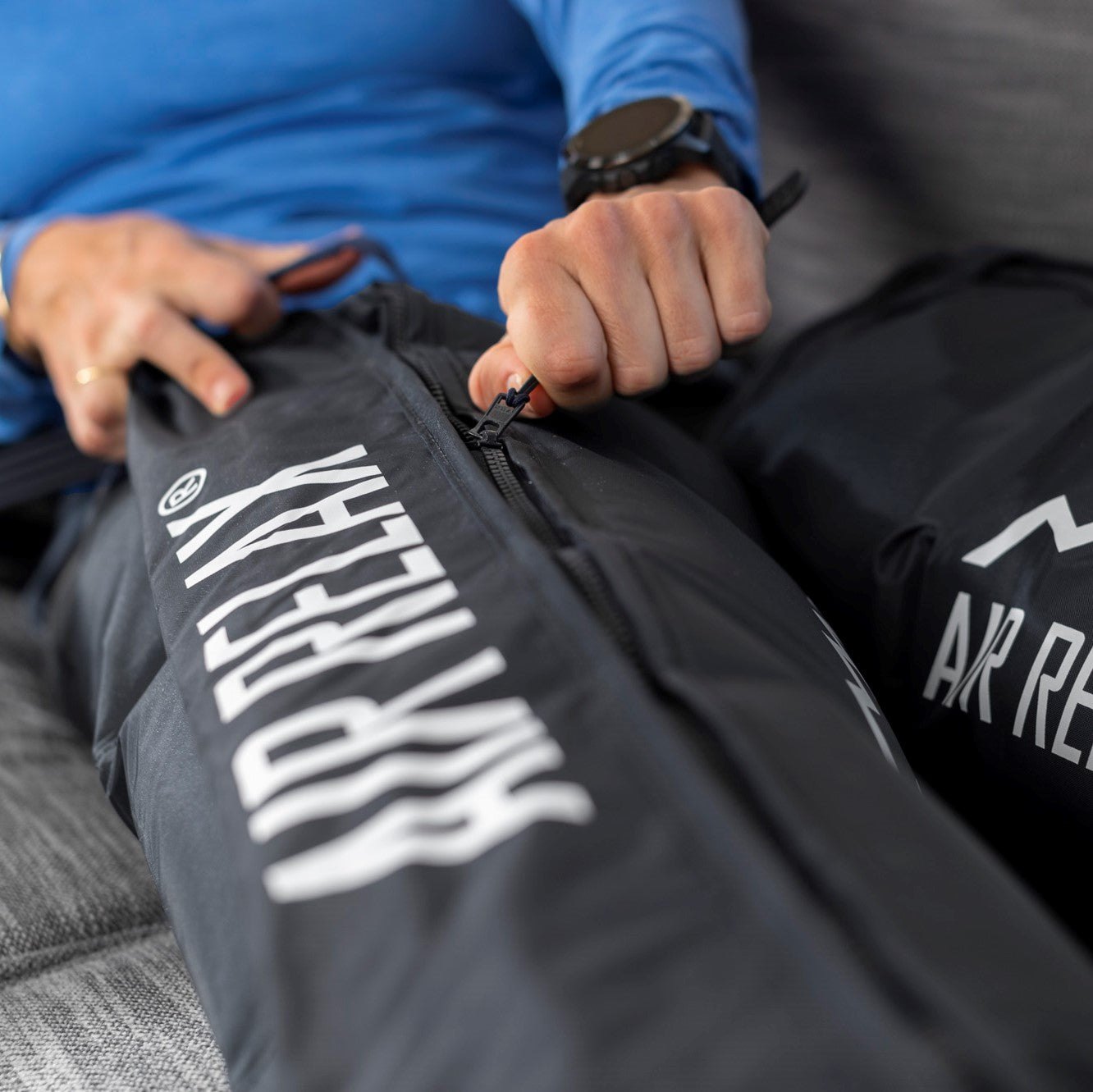 AIR RELAX AR-3.0 & AR-2.0 LEG SLEEVES — Close-up of hand zipping up a black leg sleeve