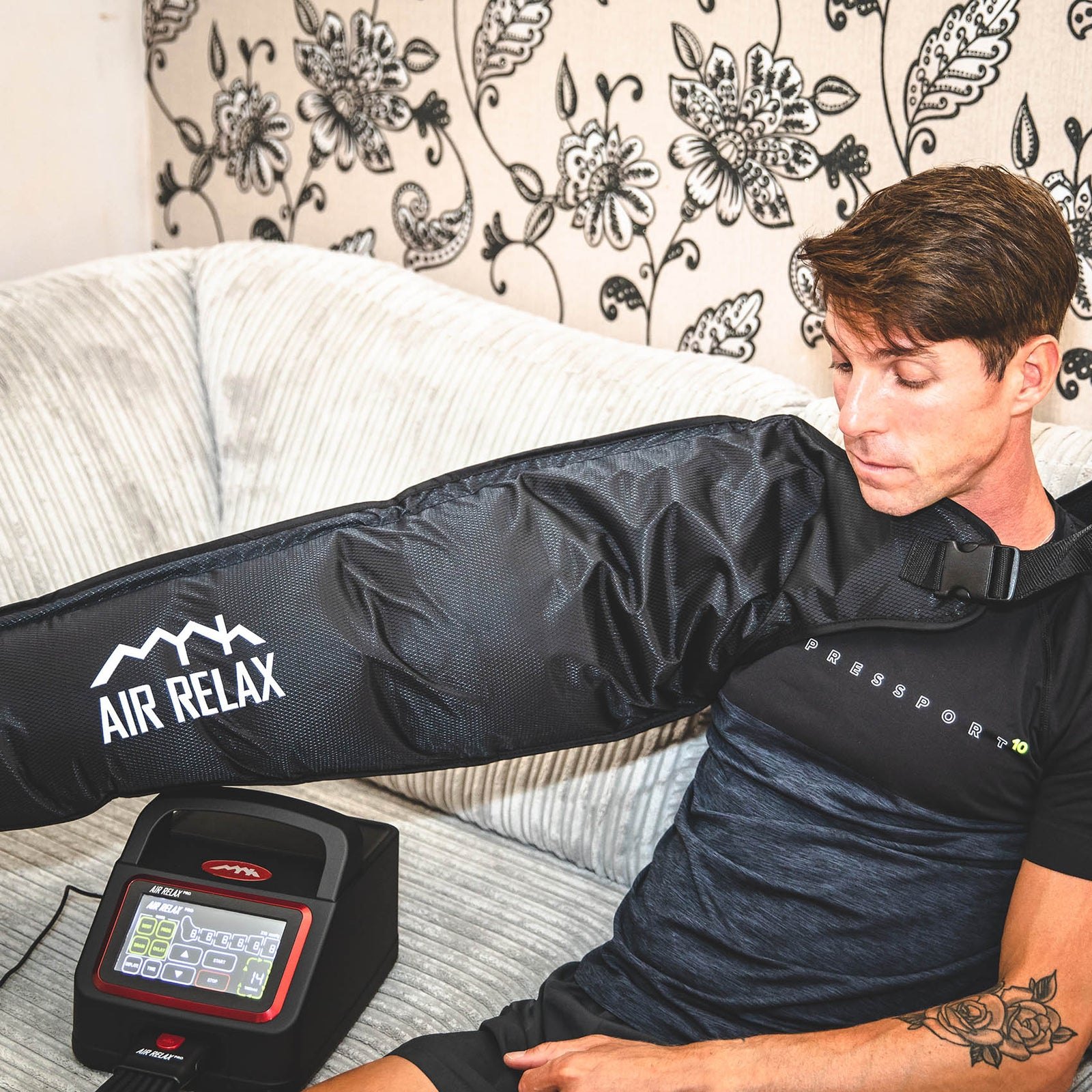 AIR RELAX PRO AR-4.0 ARM SLEEVE — Man sitting with arm sleeve inflated on couch