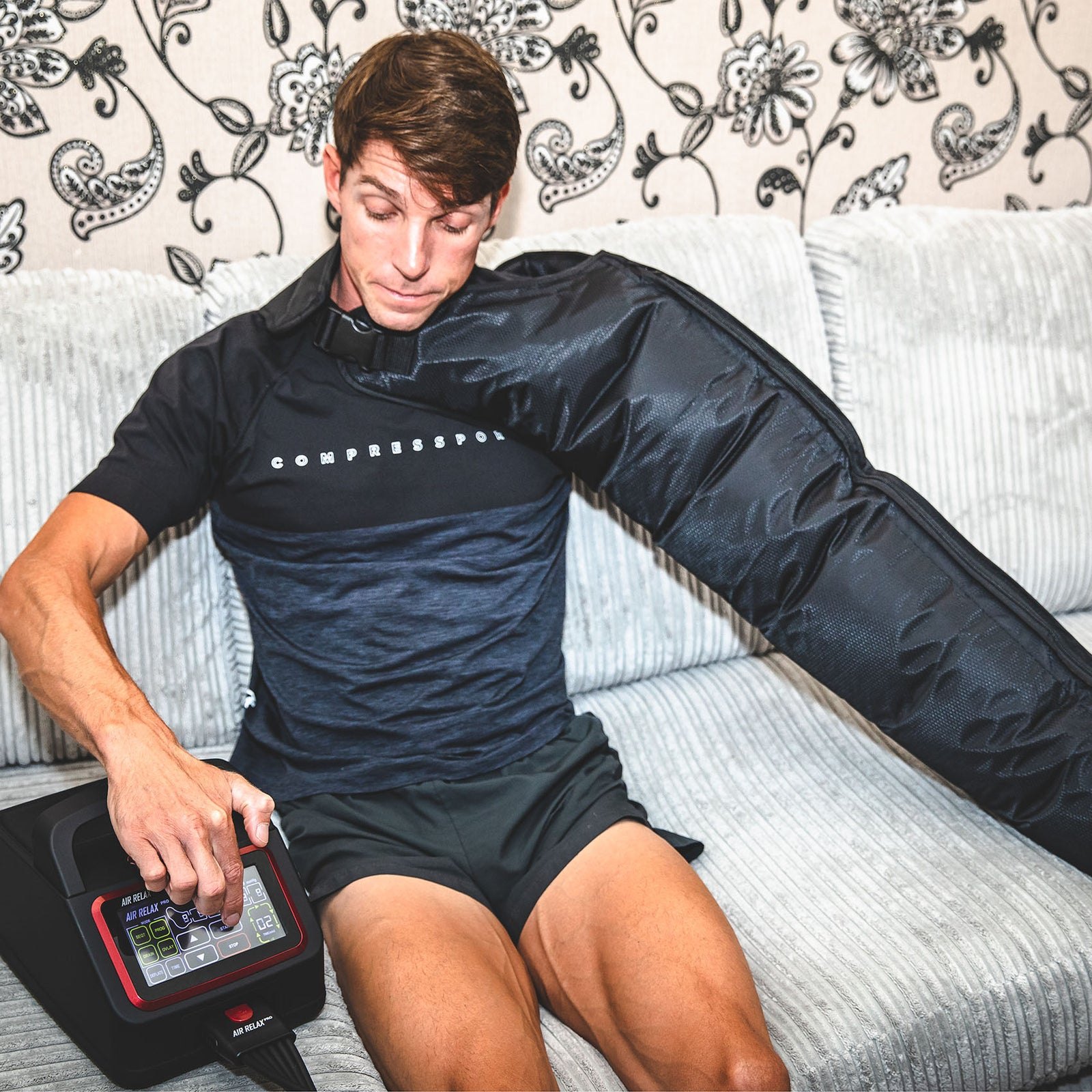 AIR RELAX PRO AR-4.0 ARM SLEEVE — Man adjusting settings on Air Relax Pro pump while wearing arm sleeve