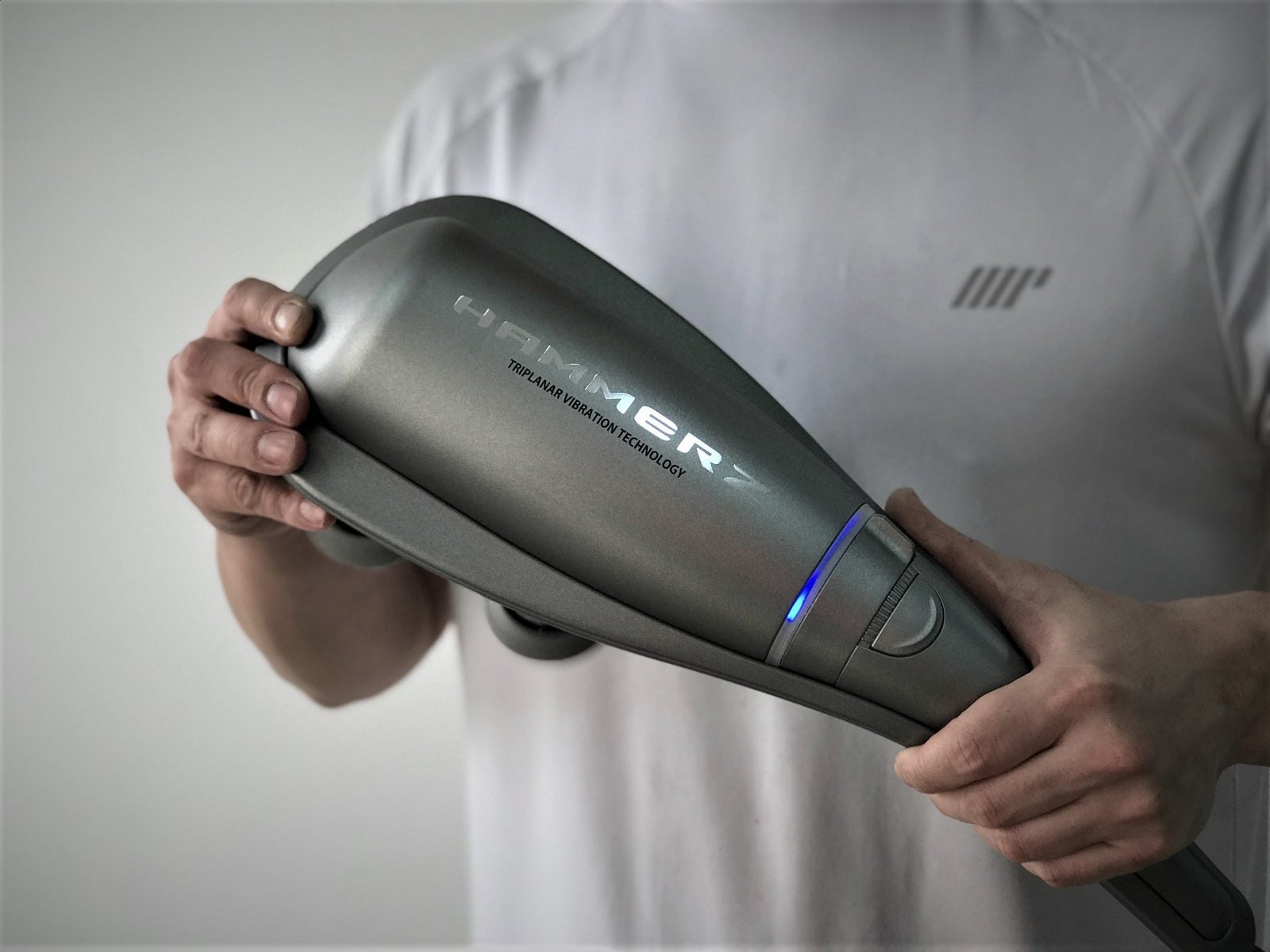 HAMMERZ MASSAGE DEVICE WITH TRIPLANAR VIBRATION TECHNOLOGY — Man holding the Hammerz massager showing the blue indicator light